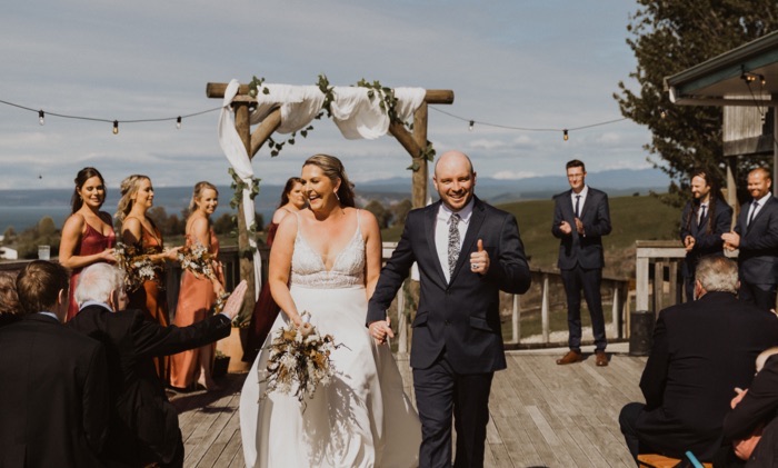 Image of bride and groom smiling at crowds